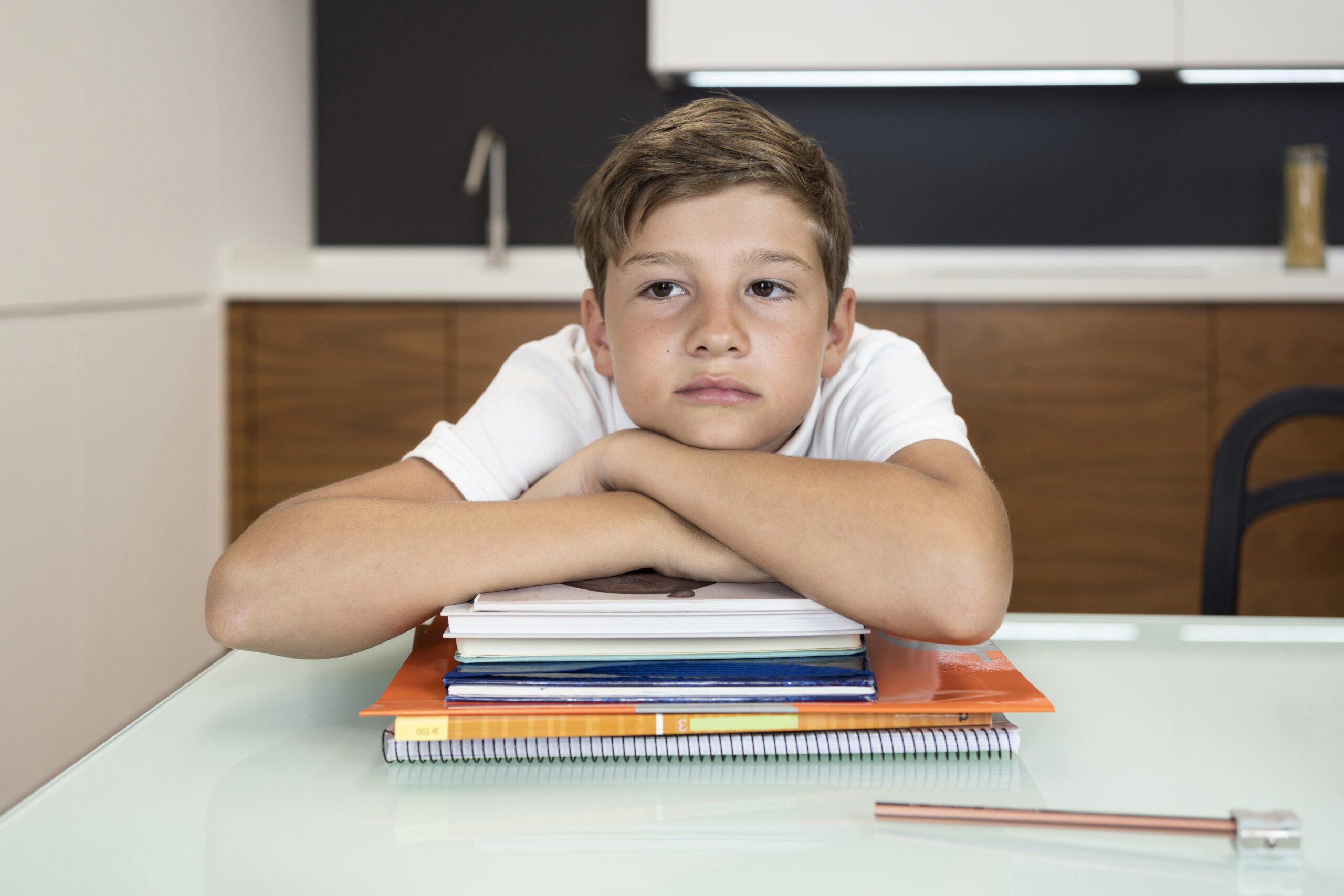 chico-altas-capacidades Niño pensativo sobre libros apilados.