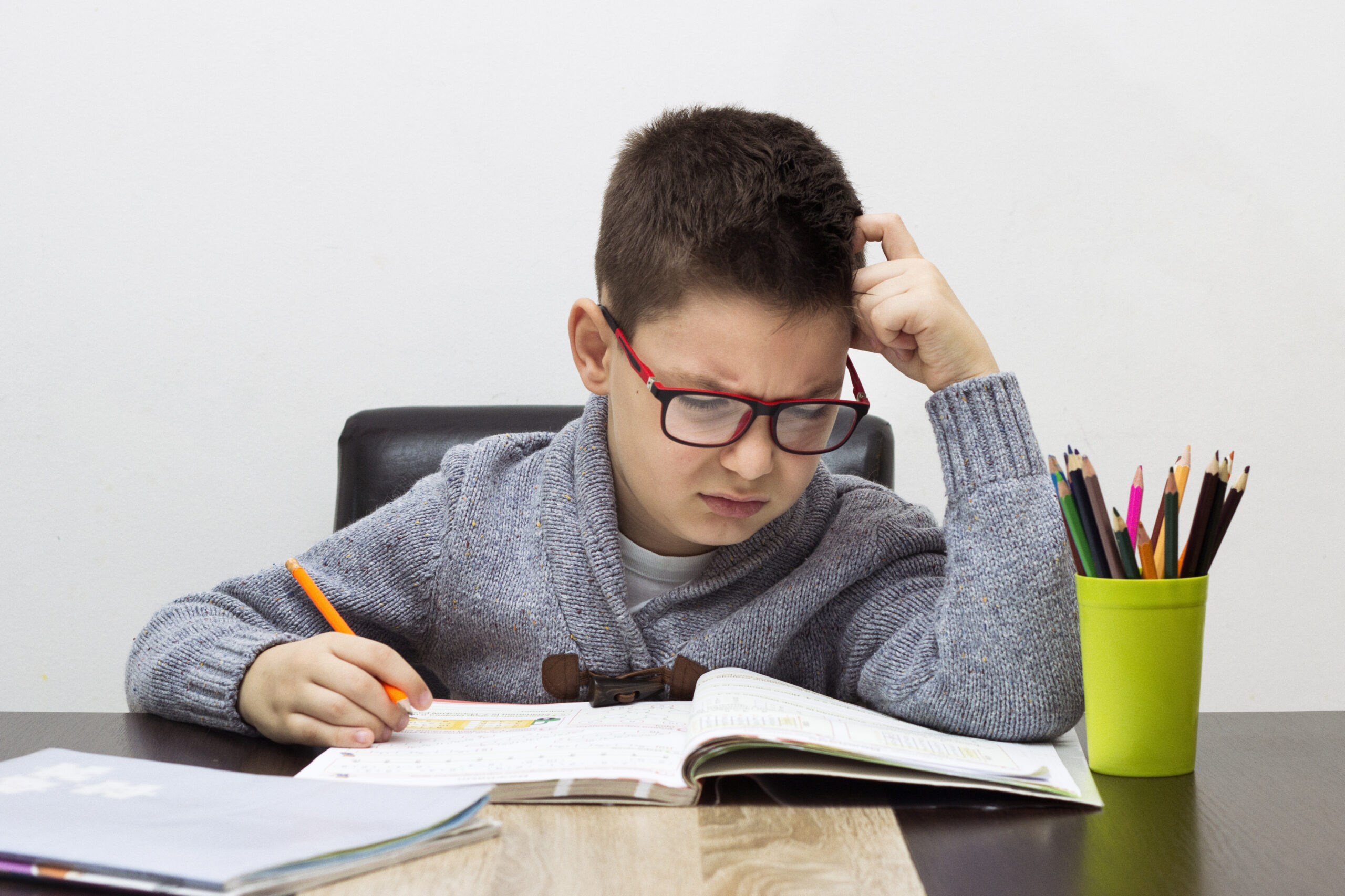 young boy frustrated over homework, writing at home. Boy studying at table. Kid drawing with a pencil Niño concentrado haciendo tareas escolares.
